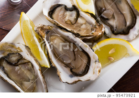 Tasty oysters with lemon on plate top view Tasty oysters with lemon on plate top view 95473921