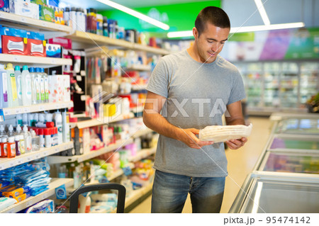 Man choosing frozen pizza dough in refrigerated display case in supermarket 95474142