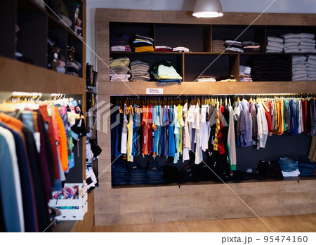 Interior of male clothing store with clothes on hangers and shelves Interior of male clothing store with clothes on hangers and shelves 95474160