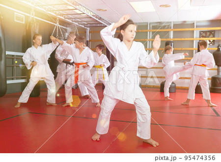 Girl practicing new moves during karate class Girl practicing new moves during karate class 95474356