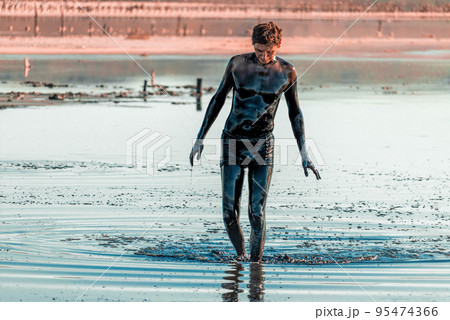 Man applying black healing clay. Mud spa on the shore of salt lake. Swimming in the nutrient-rich mud of the mud lake near the Sea of Azov, Crimea, mud lake Chokrak. Russia 95474366