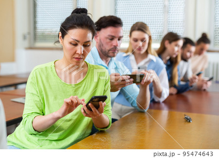Fellow students play with their smartphones 95474643