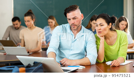Group of adult students sitting at tables in classroom Group of adult students sitting at tables in classroom 95475521