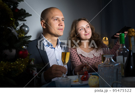 Happy couple drink champagne and watch TV on Christmas night 95475522