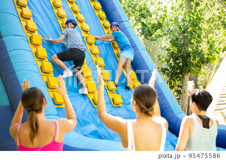 Men climbing up on slide in adventure park Men climbing up on slide in adventure park 95475586