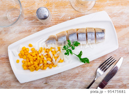 Sliced herring with corn and herbs on rectangular plate Sliced herring with corn and herbs on rectangular plate 95475681