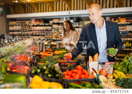 Young confident man selects fresh vegetables in the supermarket 95475724