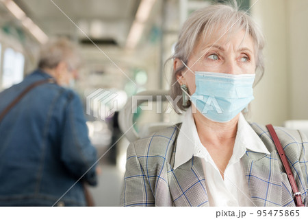 Portrait of senior woman in face mask sitting in tram 95475865