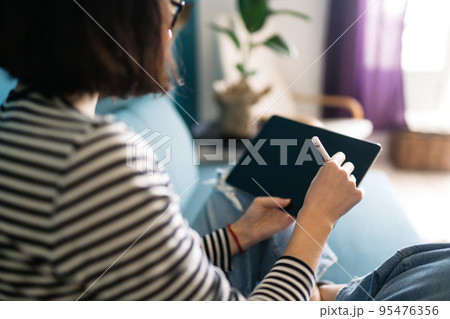 Young woman using tablet, spending leisure time chatting in social network. 95476356