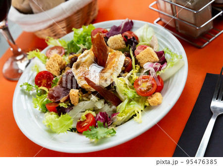 Salad from goat cheese with lettuce, meat, tomatoes and honey 95476385