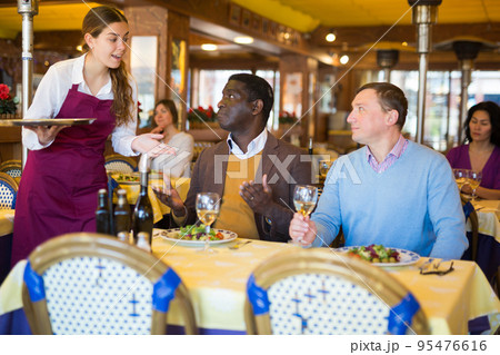 Waitress and two man of the restaurant pay for dinner using smartphones Waitress and two man of the restaurant pay for dinner using smartphones 95476616