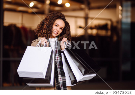Stylish woman with shopping bags 'near mall. Young woman after shopping. Winter holidays. Stylish woman with shopping bags 'near mall. Young woman after shopping. Winter holidays. 95478018
