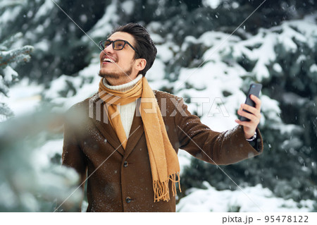 Outdoor close up portrait of young beautiful men. Smiling young man having fun outdoors. Snowfall. 95478122