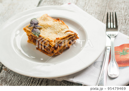 portion of lasagne bolognese on a white plate 95479469