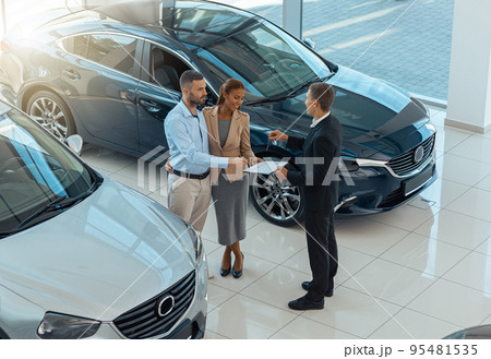 Happy beautiful couple is choosing a new car at dealership. Blurred background 95481535