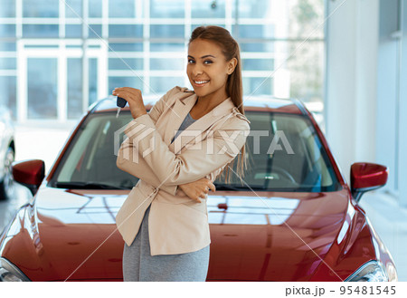 Photo of happy young woman showing key to her new car. Concept for car rental 95481545