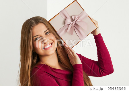 Holiday present for birthday, baby shower, wedding or luxury beauty box subscription delivery, happy woman holding a wrapped pink gift on white background 95485366