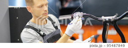 Garage service worker check wheel on motorbike, hold clipboard with info Garage service worker check wheel on motorbike, hold clipboard with info 95487849
