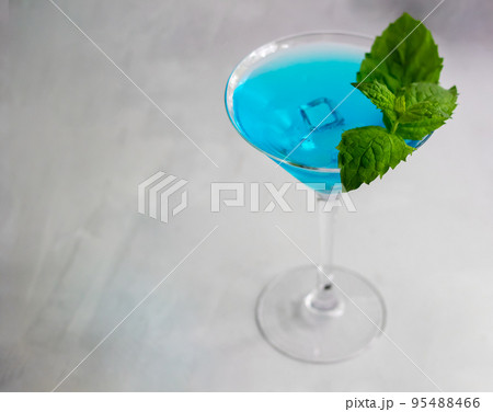 Close-up of blue cocktail in martini glass with ice cubes and mint 95488466
