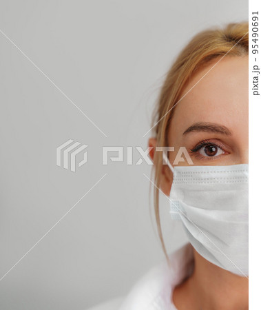 Close-up portrait of a young blonde woman in a medical mask on a light background. Virus protection. Coronovirus covid-19 The concept of a pandemic epidemic. Quarantine. Stay at home. Close-up portrait of a young blonde woman in a medical mask on a light background. Virus protection. Coronovirus covid-19 The concept of a pandemic epidemic. Quarantine. Stay at home. 95490691