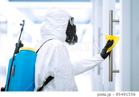 Cleaning and disinfection of office to prevent COVID-19, Man in protective hazmat suit washes office 95491556