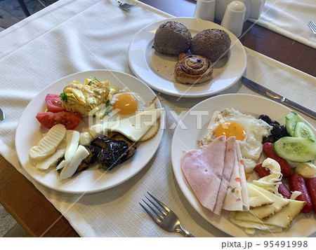 Lunch. Plates of eggs, ham, cheese and vegetables on table. Studio Photo 95491998