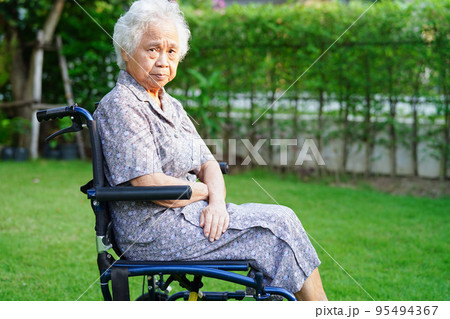 Asian elderly woman disability patient sitting on wheelchair in park, medical concept. 95494367