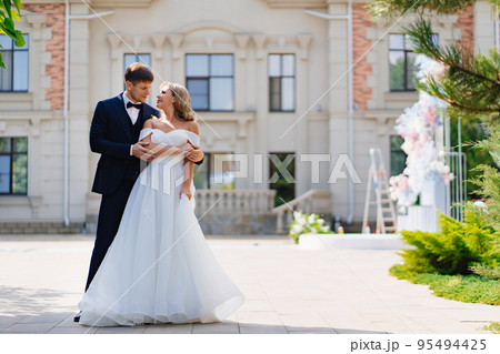 happy bride and groom dance against the backdrop of a large beautiful building. happy bride and groom dance against the backdrop of a large beautiful building. 95494425