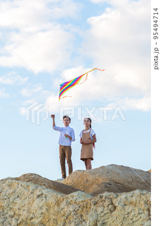 Classmates a boy and a girl launch a kite standing on the edge of the abyss Classmates a boy and a girl launch a kite standing on the edge of the abyss 95494714