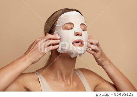 Beauty Woman Applying Face Mask. Portrait Of Girl Applying White Sheet Mask Beauty Woman Applying Face Mask. Portrait Of Girl Applying White Sheet Mask 95495128