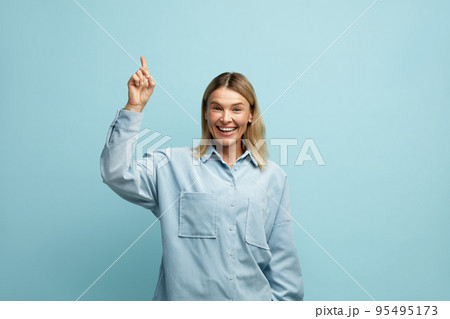 Cheerful Woman Pointing Up at Studio. Overjoyed Girl Points Finger Empty Space 95495173