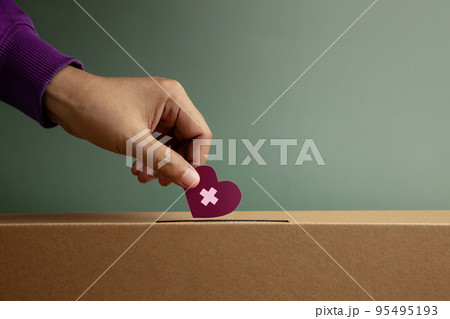 Donation Concept. Hand Drop a Paper Heart with Cross into a Donate Box. Helping, Supporting and Togetherness. Side View 95495193