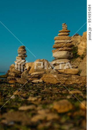 Laying beach stones balancing rocks on a sand seashore Laying beach stones balancing rocks on a sand seashore 95495484