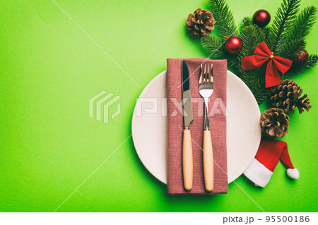 Christmas table place setting with christmas decor and plates, kine, fork and spoon. Christmas holiday background. Top view with copy space 95500186