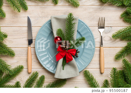 Christmas table place setting with christmas decor and plates, kine, fork and spoon. Christmas holiday background. Top view 95500187