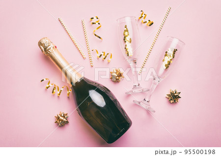 bottle of champagne with glasses and colorful confetti on colored background. top view flay lay 95500198