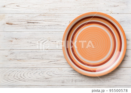 Top view of empty orange plate on wooden background. Empty space for your design 95500578