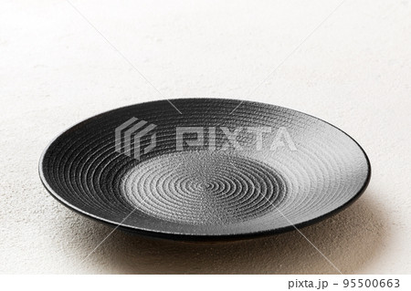 Perspective view of empty black plate on cement background. Empty space for your design Perspective view of empty black plate on cement background. Empty space for your design 95500663