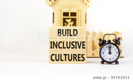 Build inclusive cultures symbol. Concept words Build inclusive cultures on blocks. Black alarm clock. Beautiful white table white background. Business build inclusive cultures concept. Copy space. Build inclusive cultures symbol. Concept words Build inclusive cultures on blocks. Black alarm clock. Beautiful white table white background. Business build inclusive cultures concept. Copy space. 95502651