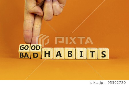 Good or bad habits symbol. Businessman turns wooden cubes and changes words 'bad habits' to 'good habits'. Beautiful orange table, orange background. Business, bad or good habits concept. Copy space. 95502720
