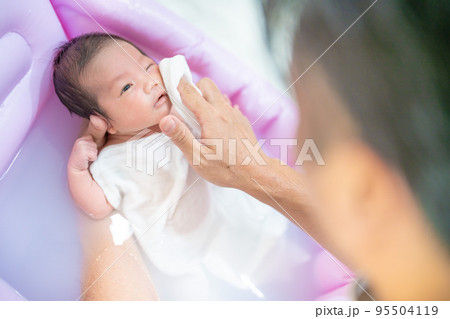 沐浴で顔を洗われる赤ちゃん（新生児・パパ・父・子供・子ども・0歳・育児・子育て・お風呂・入浴） 95504119