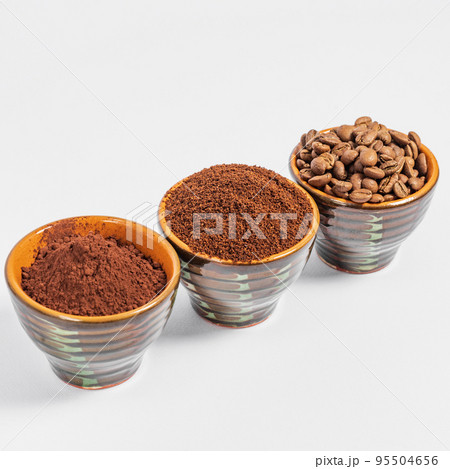 three small saucers with coffee beans, ground coffee and cocoa on a white background. three small saucers with coffee beans, ground coffee and cocoa on a white background. 95504656