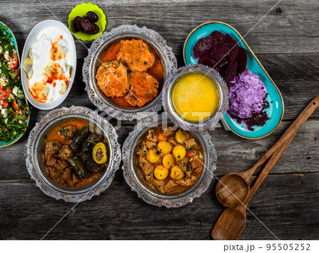 Eid Mubarak Traditional Ramadan Iftar dinner. Assorted tasty food in authentic rustic dishes on wooden blue background. Turkish Bosnian food meat kebab, pita, Sarma, klepe, sogan dolma. 95505252