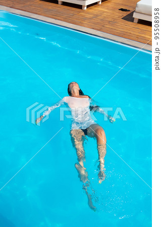 Sensual lady in wet dress standing in pool during summer vacation Sensual lady in wet dress standing in pool during summer vacation 95508958