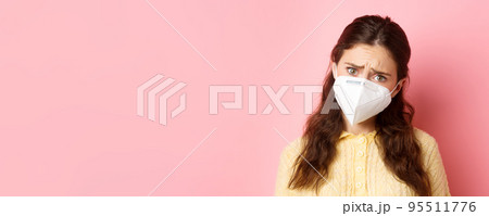 Preventive measures, health care concept. Close up of sad young woman in medical respirator express compassion, look with pity and upset face, standing against pink background 95511776