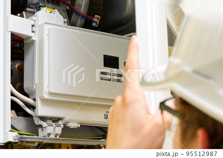 Technician servicing or Repair of a gas boiler, setting up and servicing. gas boiler for heating 95512987