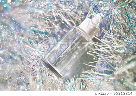 A bottle of serum with a pipette in tinsel in a Christmas theme in purple shades. 95515814