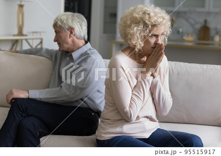 Older couple sit apart in couch feel dissatisfied with relations 95515917