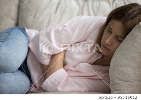 Woman feels unwell, looks unhealthy, lying on sofa at home Woman feels unwell, looks unhealthy, lying on sofa at home 95516012
