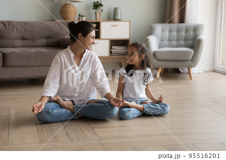 Indian woman laughing seated cross-legged doing meditation with daughter Indian woman laughing seated cross-legged doing meditation with daughter 95516201